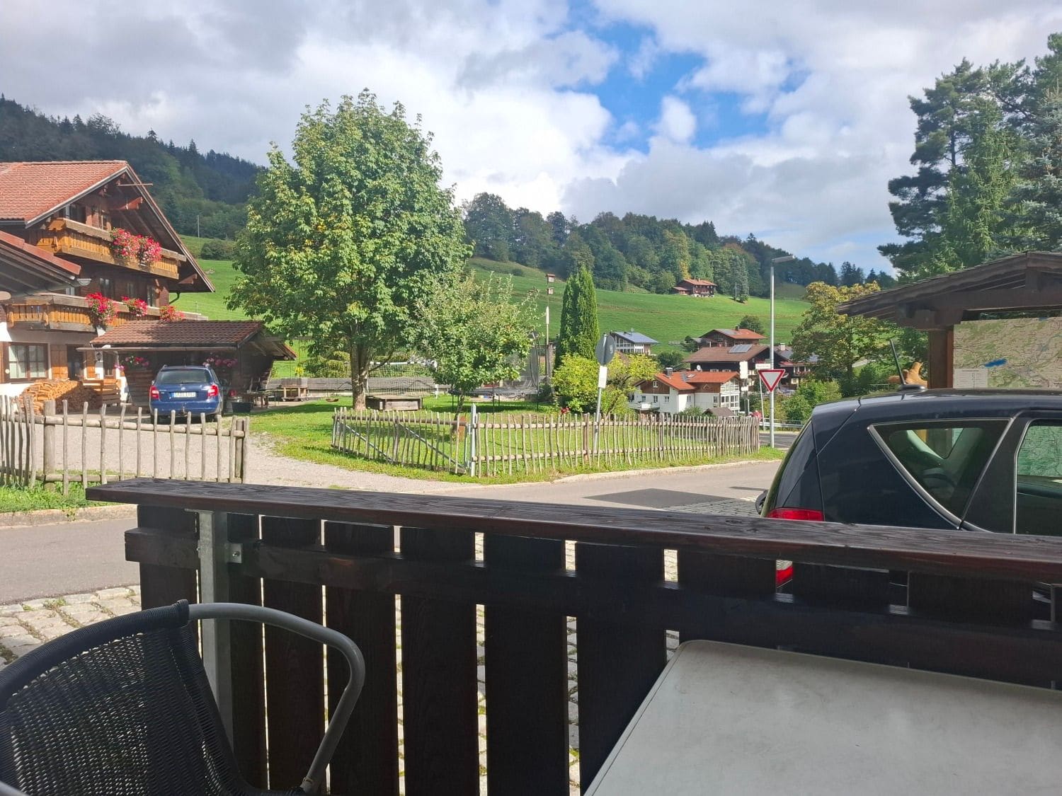 Blick von der Terrasse über Dorf, Wiesen und Berge