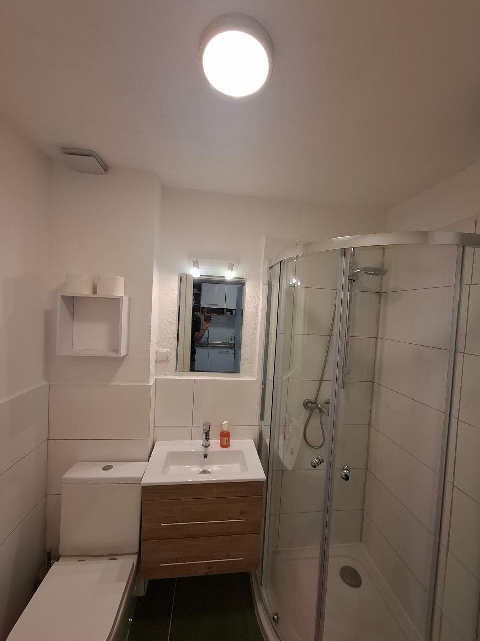 Badezimmer mit Dusche, WC und Waschbecken mit Holzunterschrank