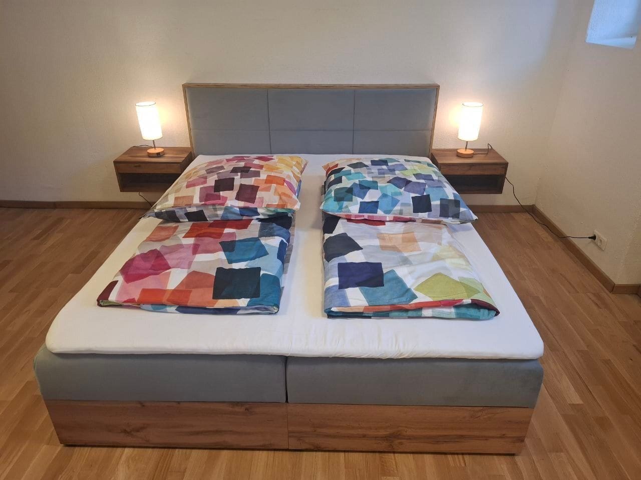 Doppelbett mit zwei Bettdecken, Nachttischen und Nachttischlampen